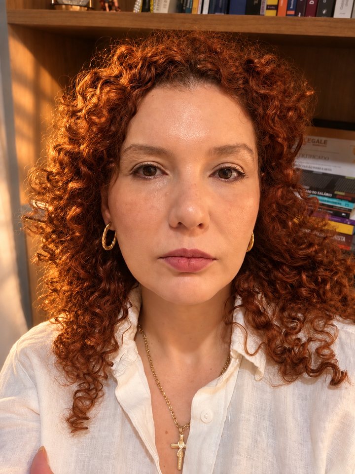 Retrato de Marenn Paixão, advogada, diante de uma estante de livros